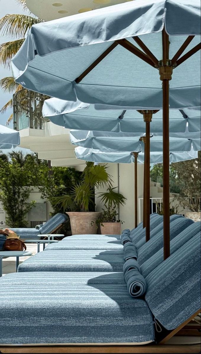 Luxury resort pool lounge with pale blue umbrellas and daybeds